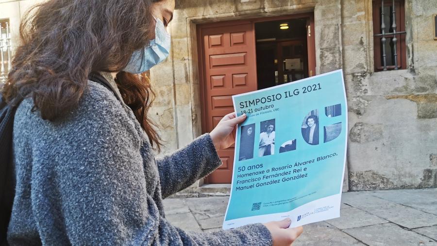 Muller con póster do simposio diante do ILG